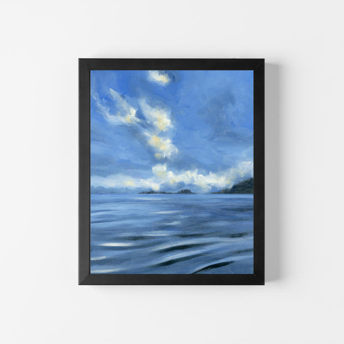A framed landscape painting of a blue sea under a cloudy sky, displayed on a clean white wall.